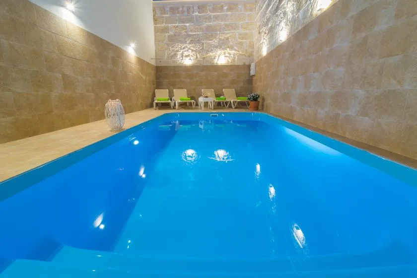 Una piscina cubierta con asientos junto a la pared del fondo.