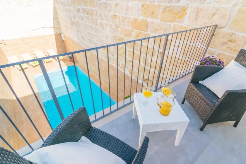 Una pequeña zona de estar al aire libre da a una piscina azul brillante.