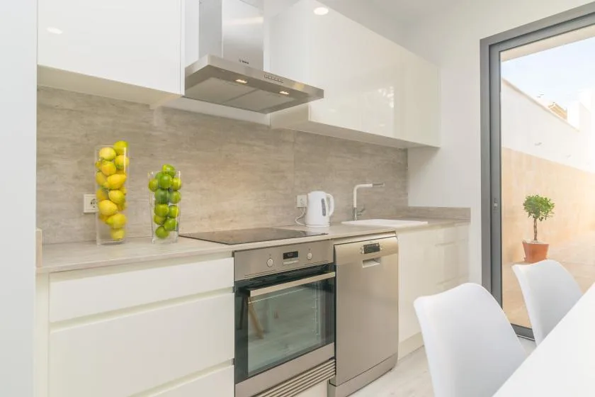 Una cocina moderna y luminosa con gabinetes blancos, encimera y electrodomésticos de acero inoxidable.