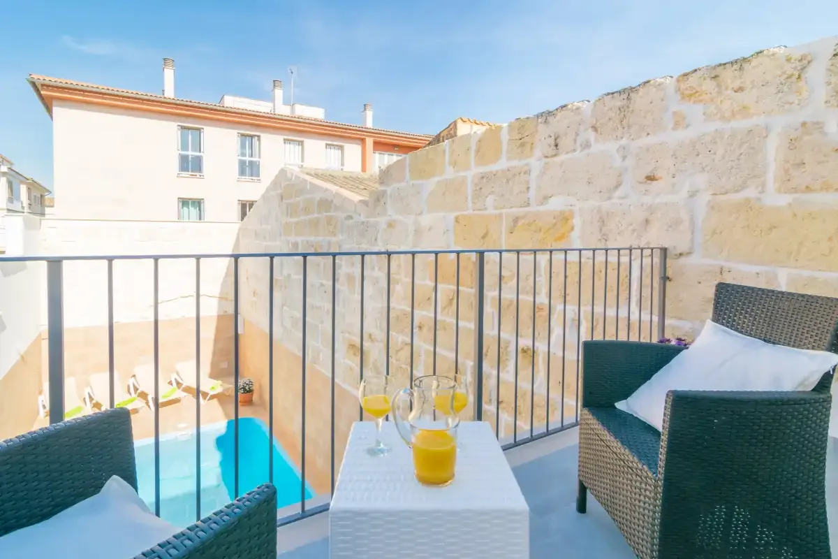Una terraza en la azotea da a una piscina, con asientos exteriores y una mesa pequeña.