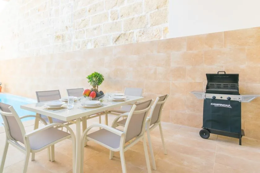 An outdoor dining area with a table set beside a barbecue grill.