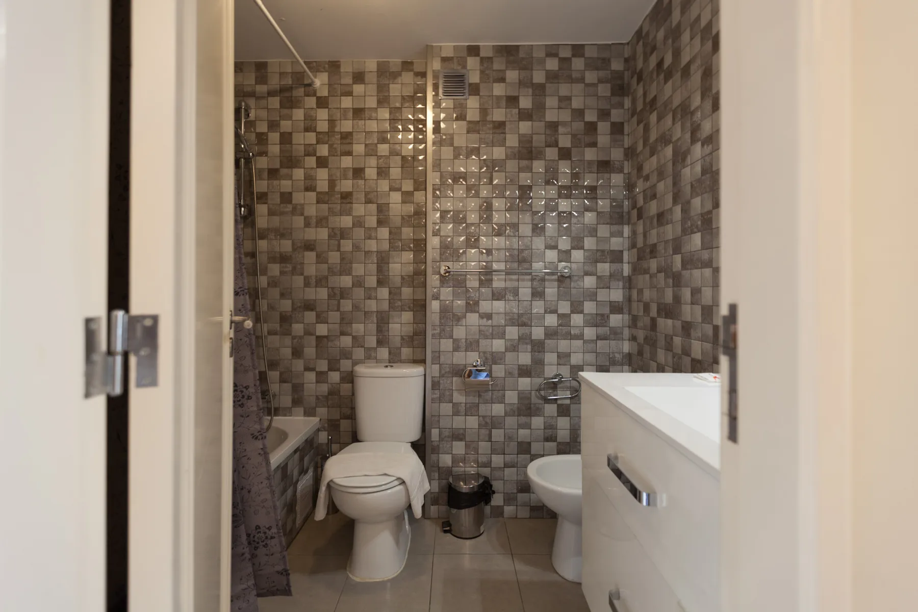 Un baño con inodoro, lavabo y paredes revestidas de azulejos.