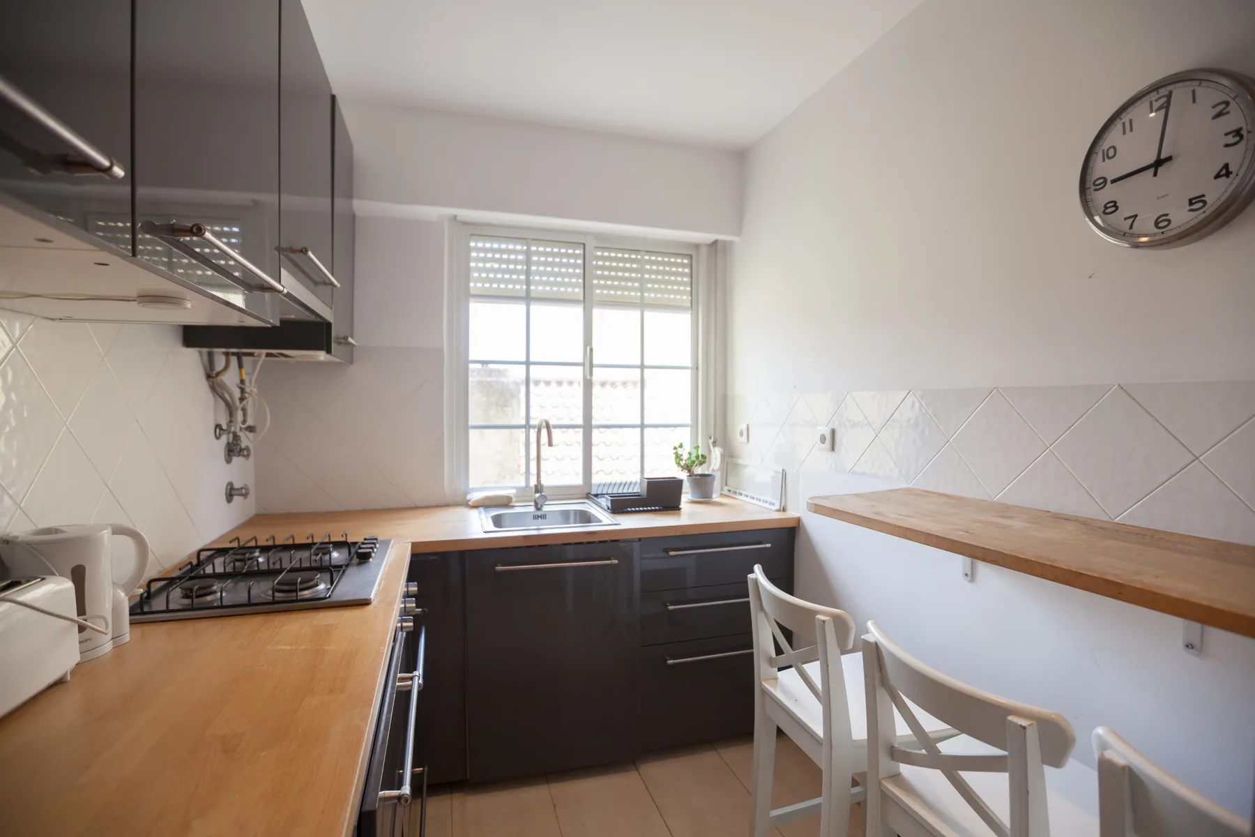 Una cocina luminosa con armarios oscuros, una placa de cocina y una ventana.