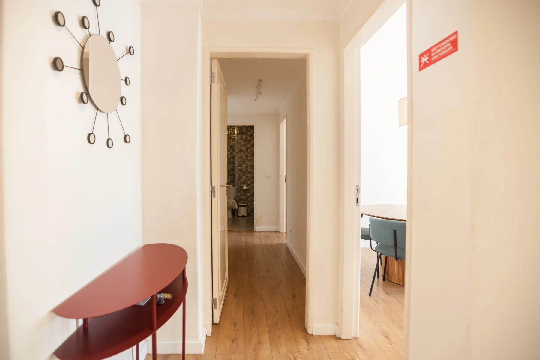 Un pasillo luminoso del apartamento da a una habitación con escritorio y silla.