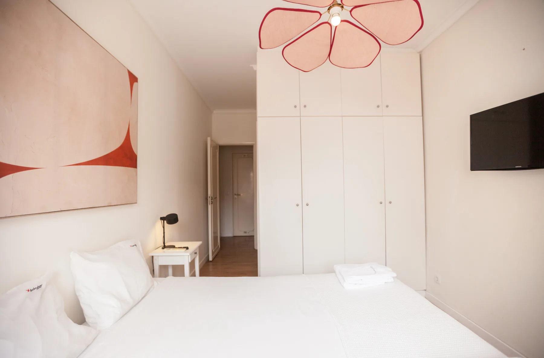 Un dormitorio con una cama blanca, armarios empotrados y arte abstracto en la pared.