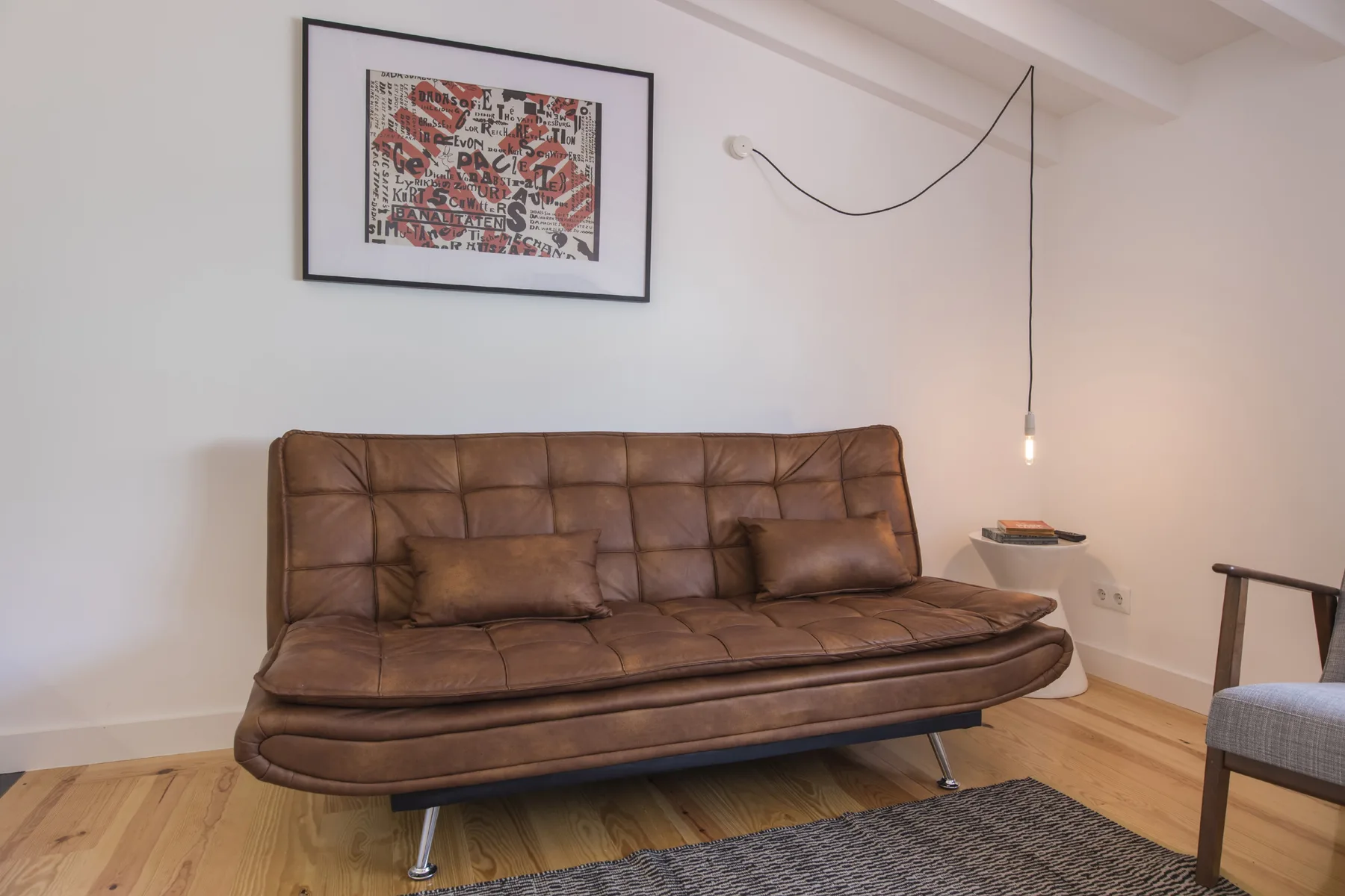 Una sala de estar con asientos marrones, arte enmarcado y una lámpara colgante.