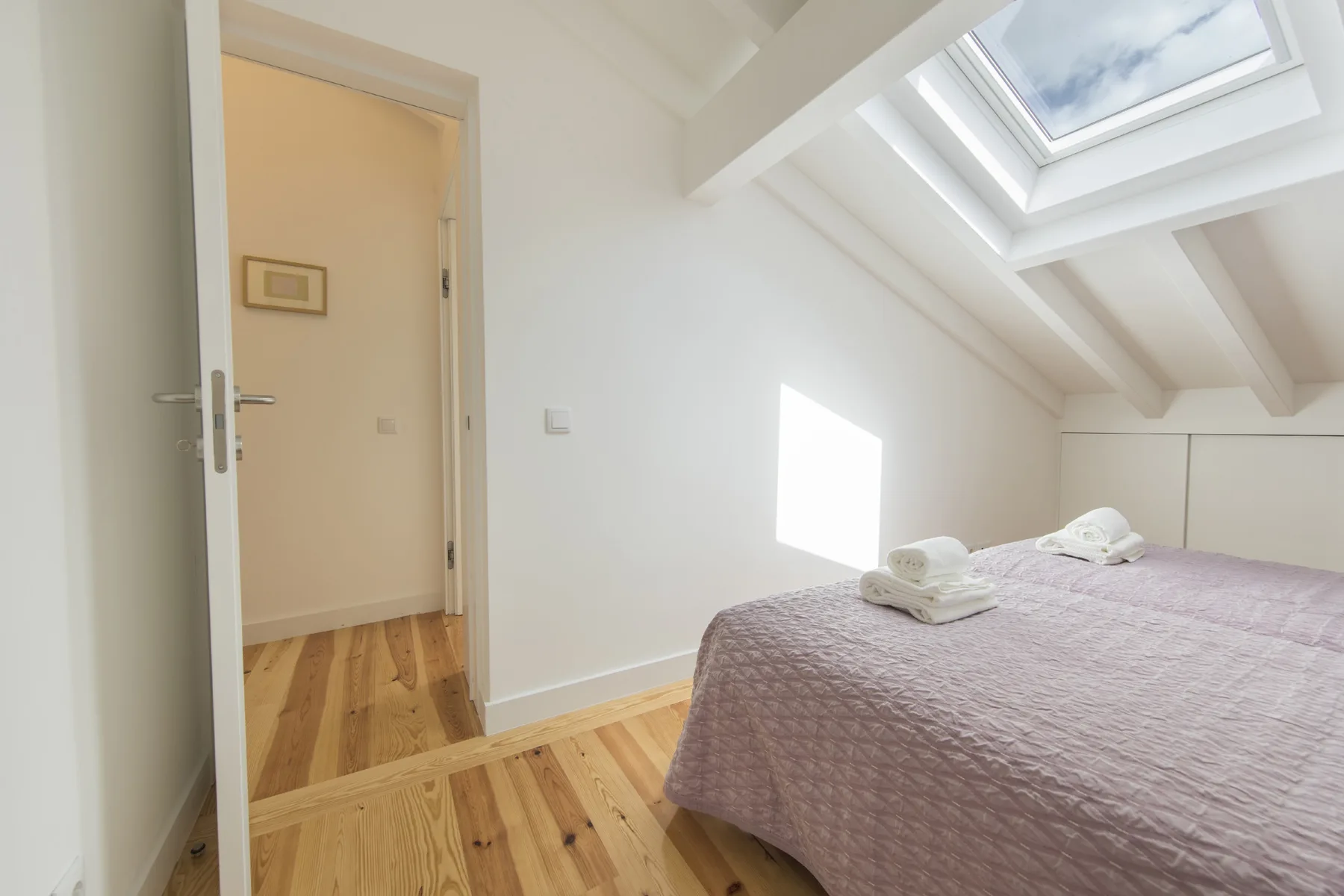 Un dormitorio abuhardillado luminoso con una cama bajo una claraboya.