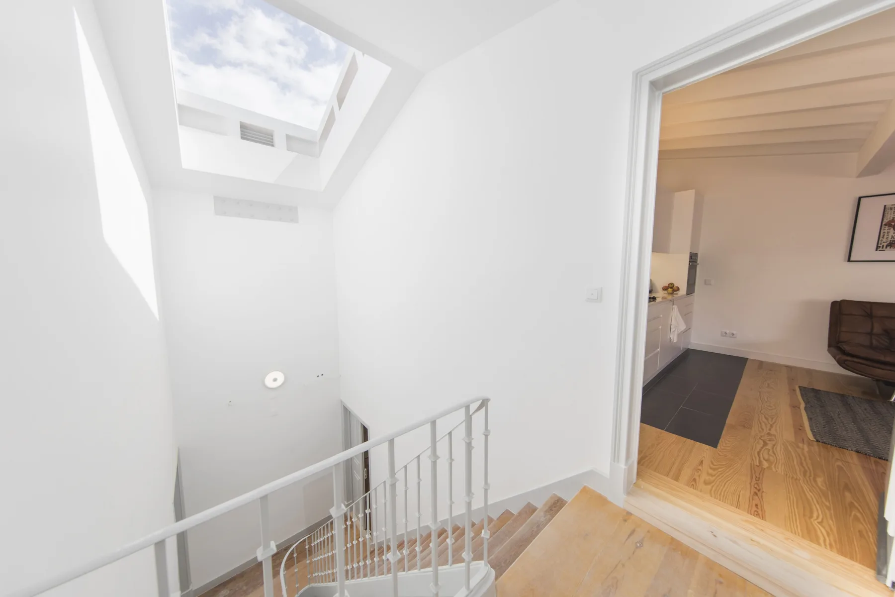 Una escalera luminosa con tragaluz se abre a una sala de estar.
