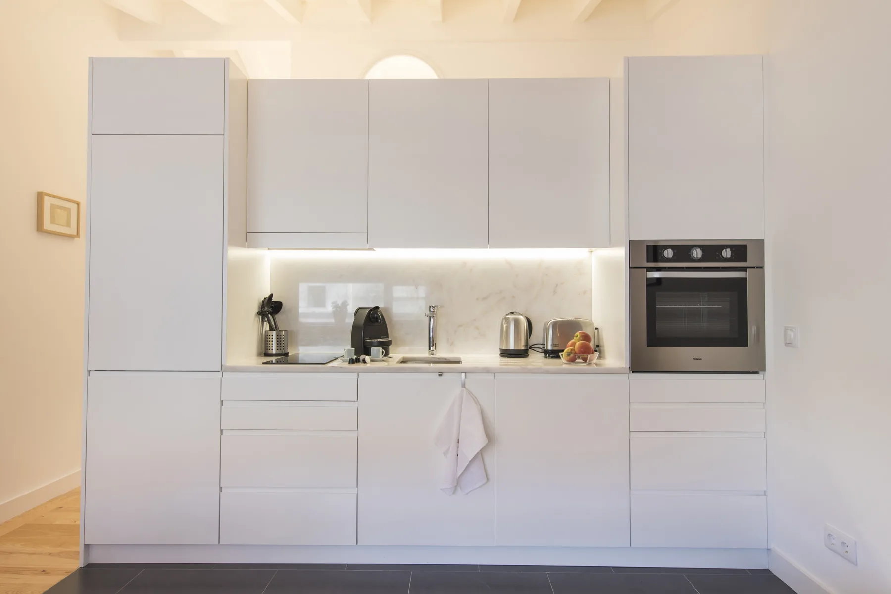Una cocina moderna con gabinetes blancos, una encimera y electrodomésticos integrados.