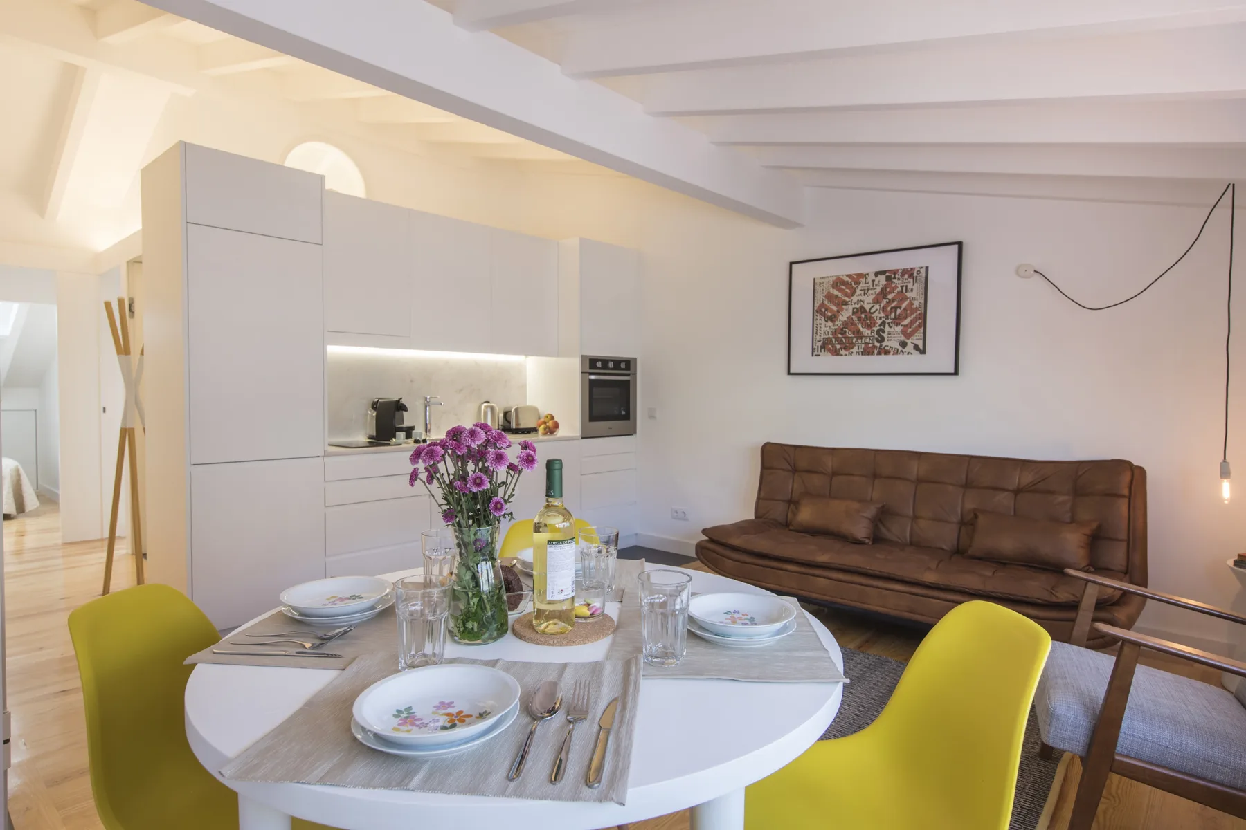Comedor y sala de estar de planta abierta con una mesa blanca y asientos marrones.