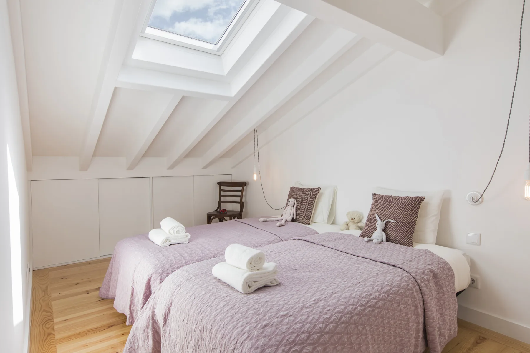 Un dormitorio luminoso con dos camas bajo una claraboya.