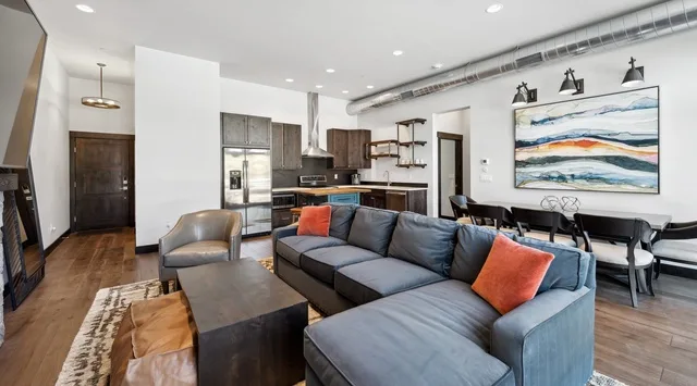 A bright open-plan living and dining area with a sectional sofa and large wall art.