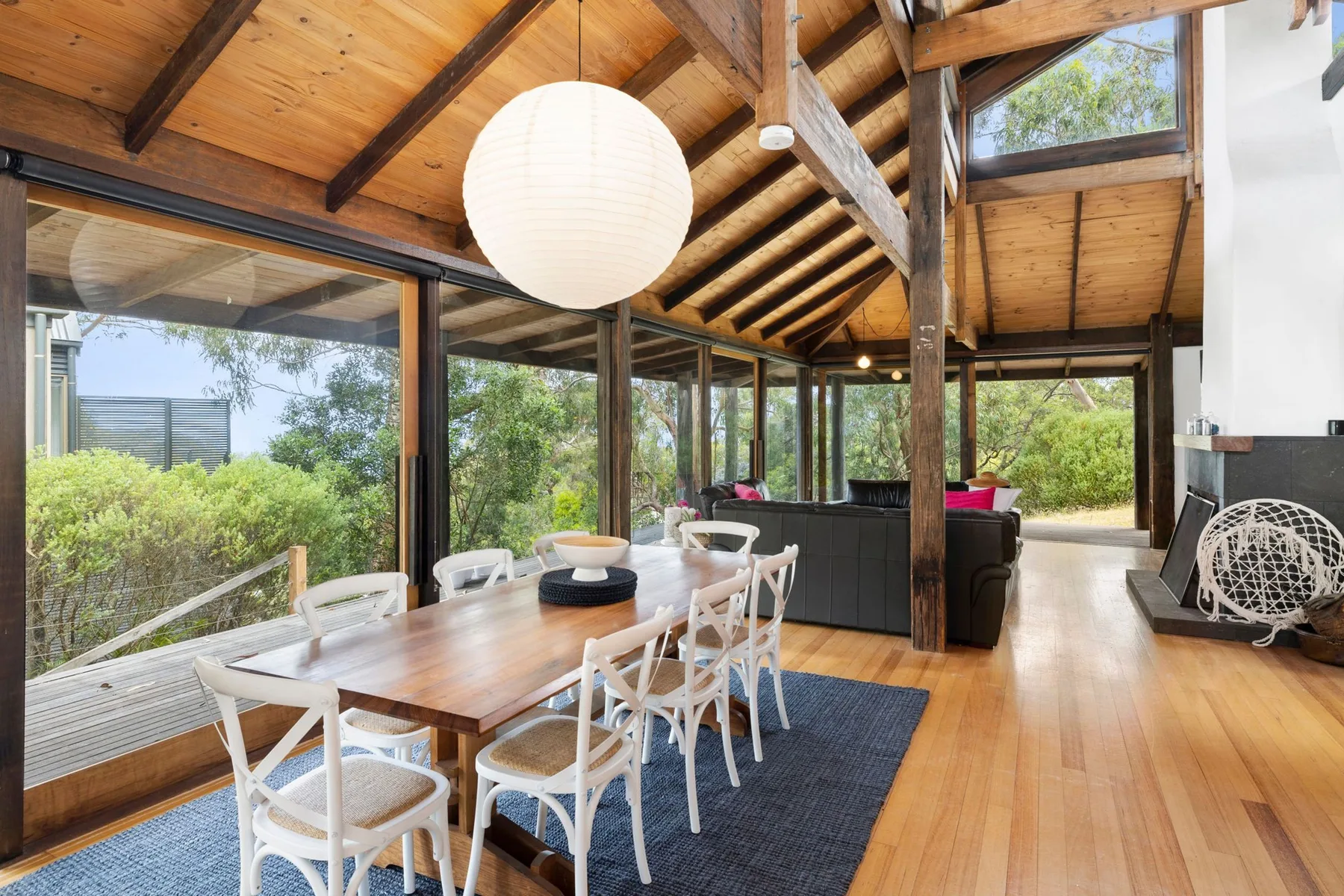 A dining area with a long table and seating beneath a timber ceiling.