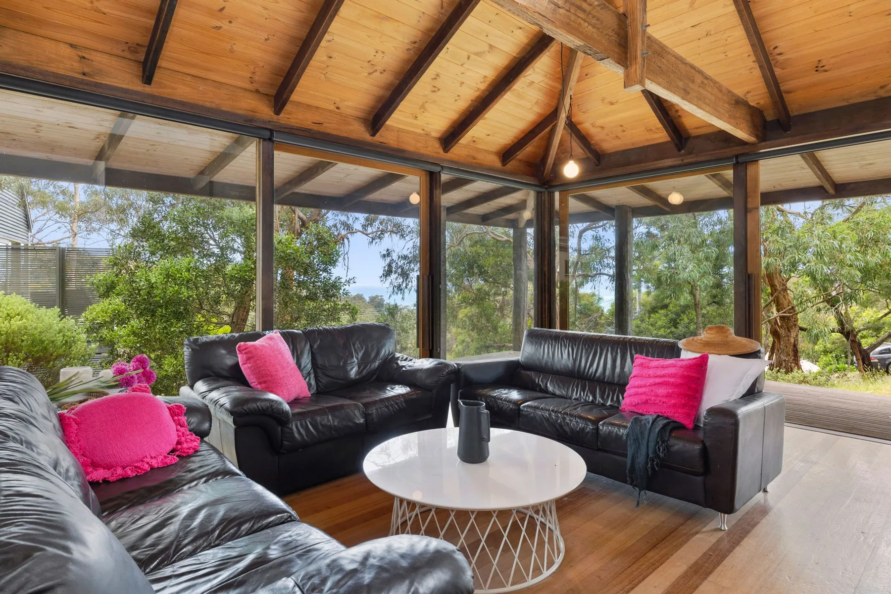 A glass-walled living room with black seating and a round coffee table.