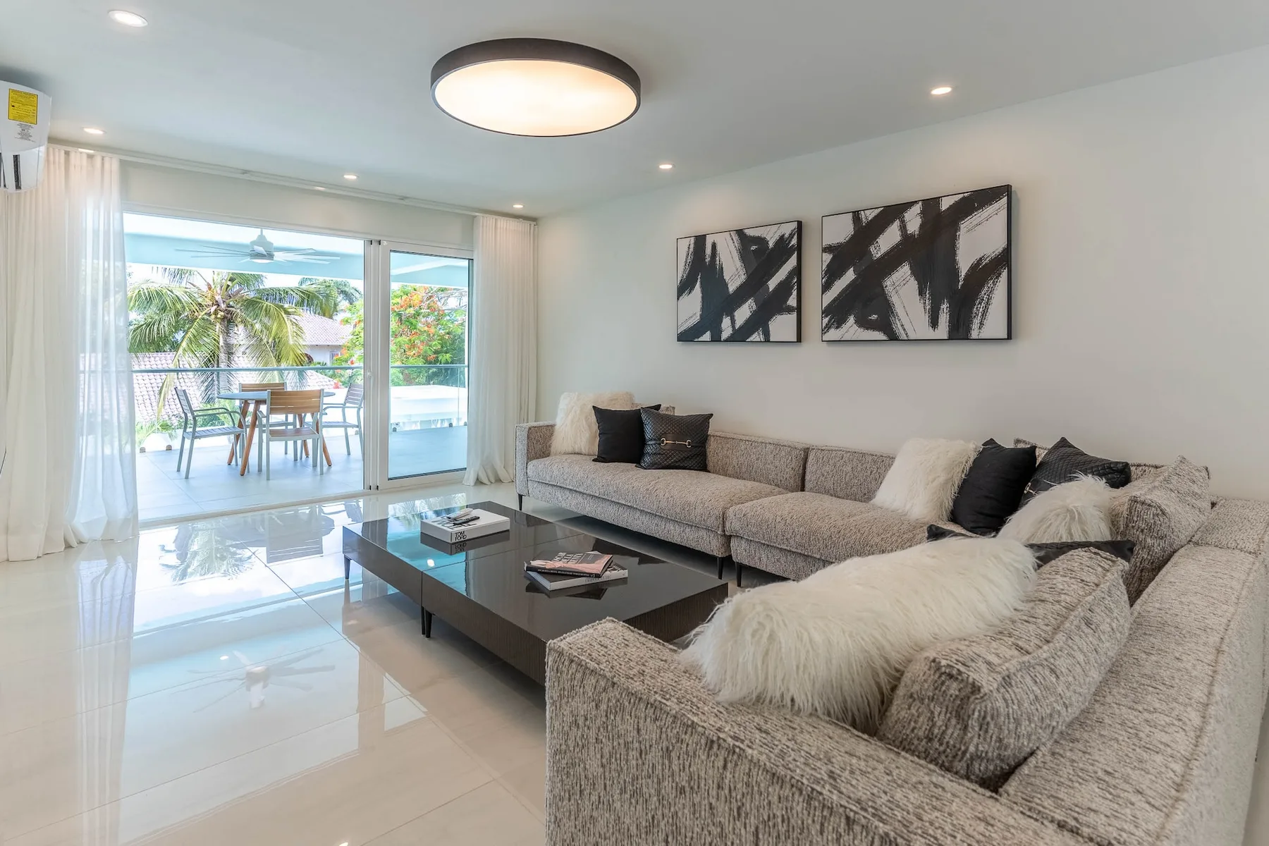 Una sala luminosa con asientos seccionales y puertas corredizas de vidrio que dan a un balcón.
