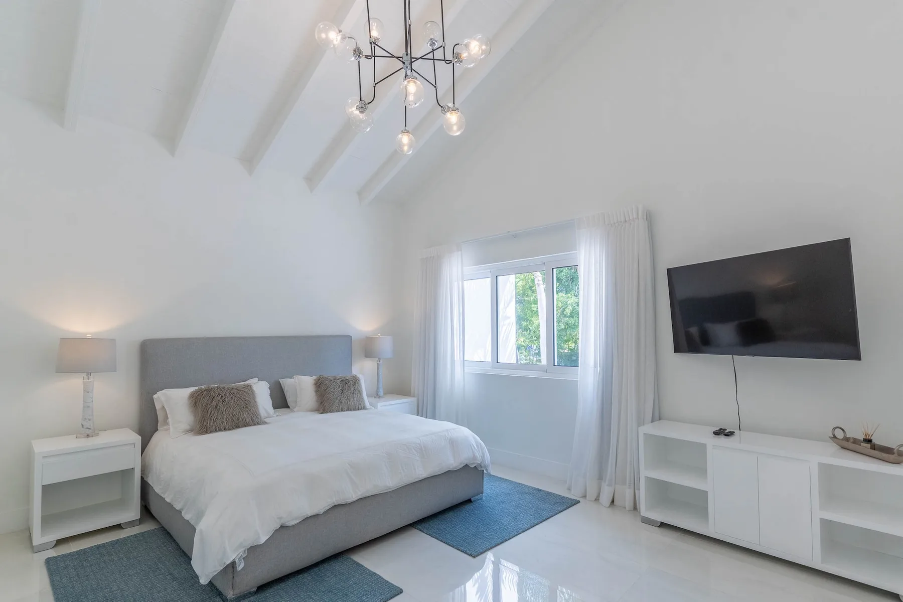 Un dormitorio luminoso con una cama bajo un techo inclinado y una ventana.