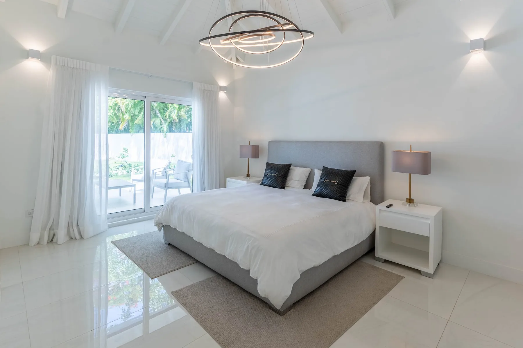 Un dormitorio luminoso con una cama y puertas de vidrio que dan a un balcón.