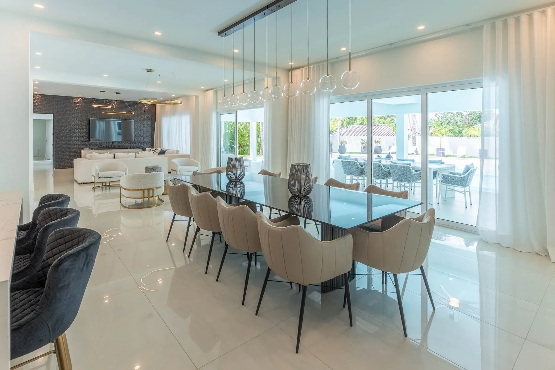 Un comedor luminoso con una mesa de vidrio y grandes ventanas hacia un patio.