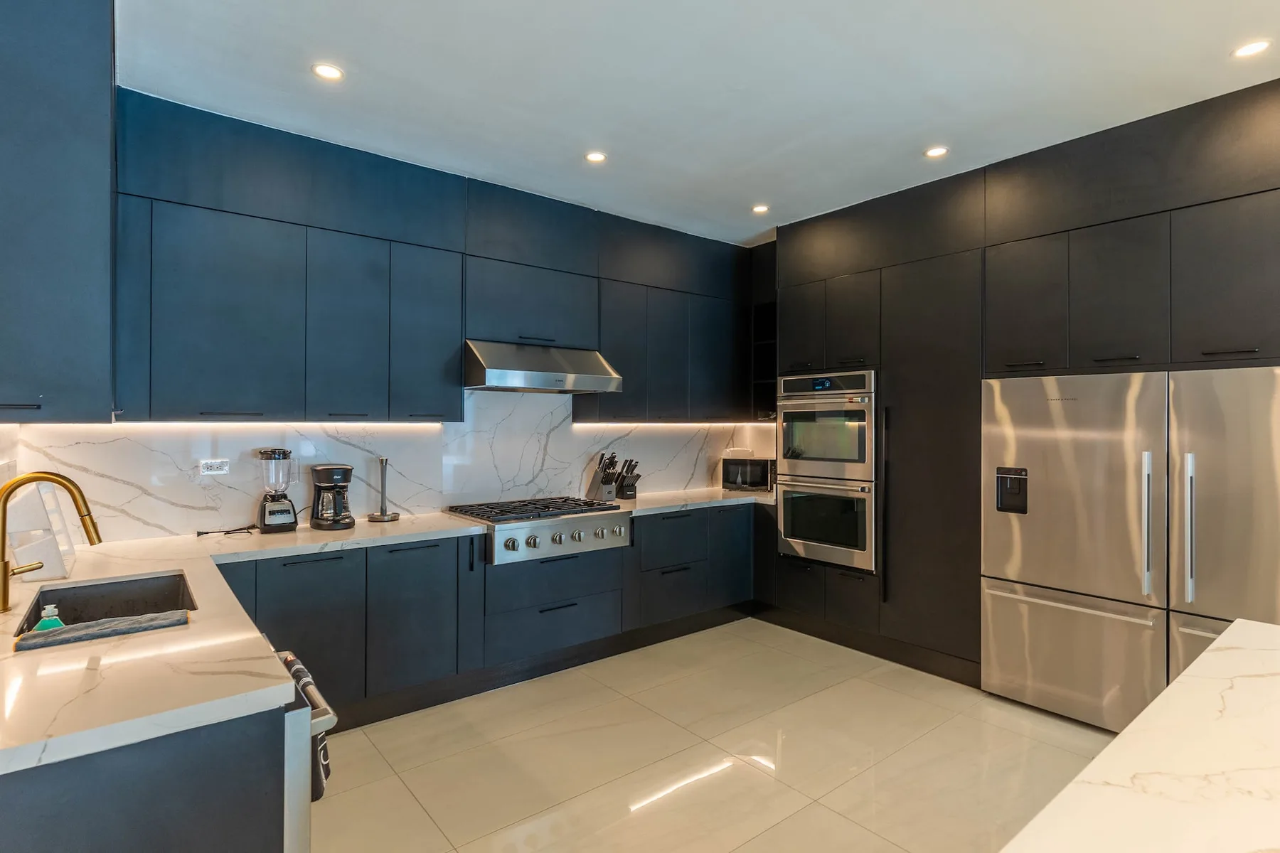 Una cocina moderna con gabinetes oscuros, electrodomésticos de acero inoxidable y encimeras claras.