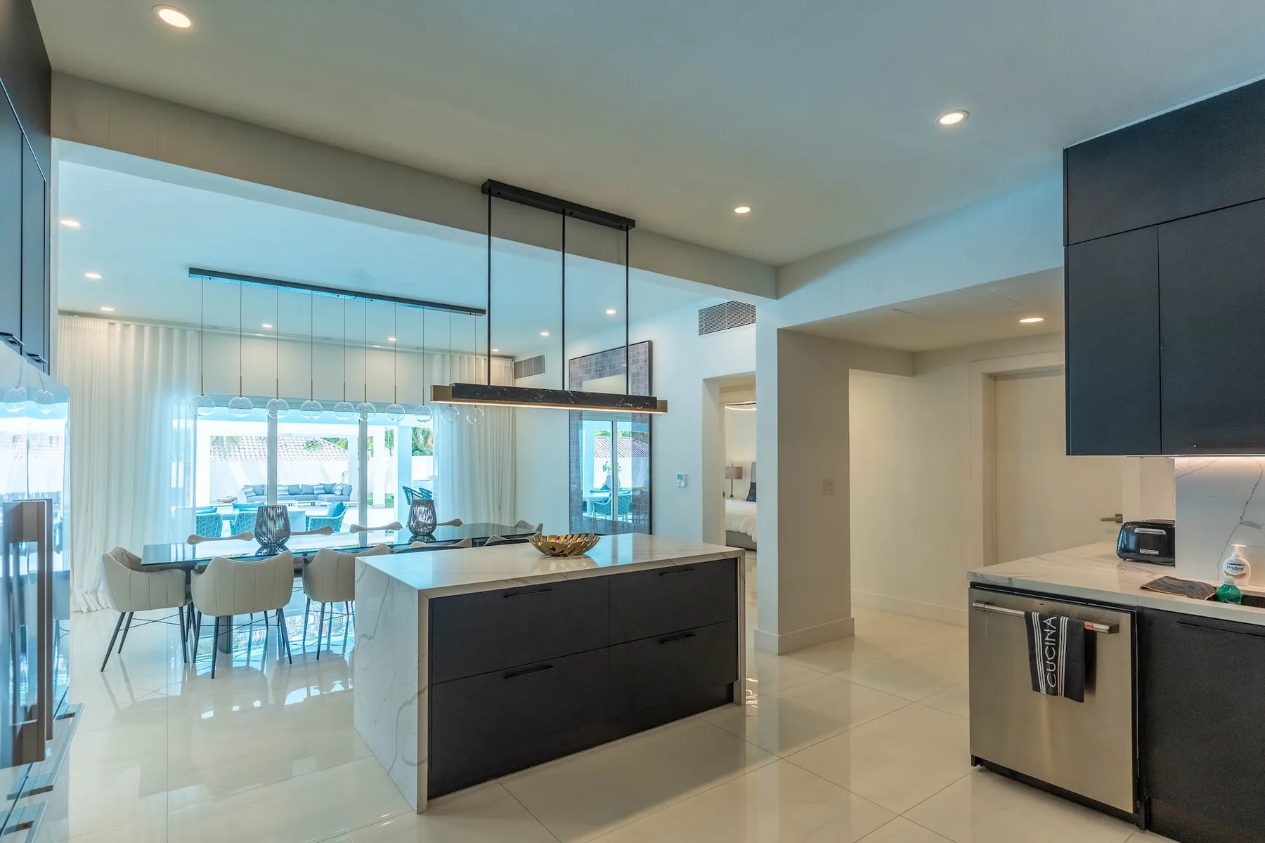 Una cocina y comedor modernos de planta abierta, con una isla central y grandes ventanales.