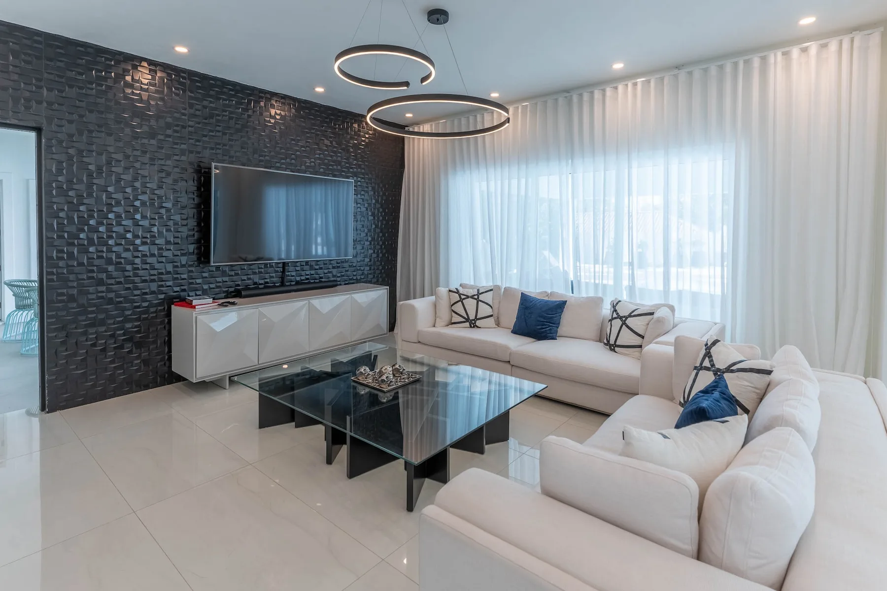A bright living room with seating arranged around a glass coffee table.