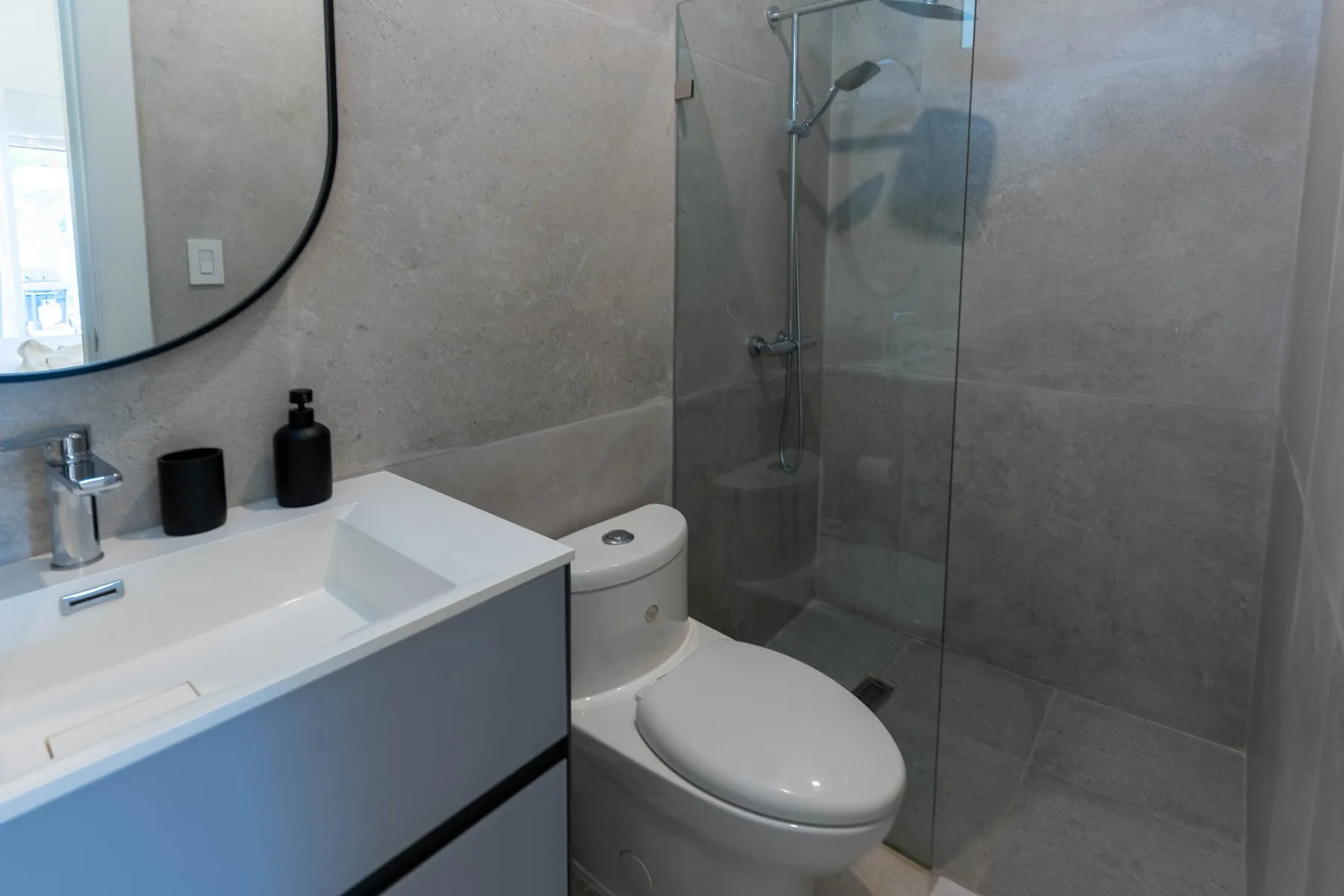 Un baño moderno con lavabo, inodoro y ducha de cristal.