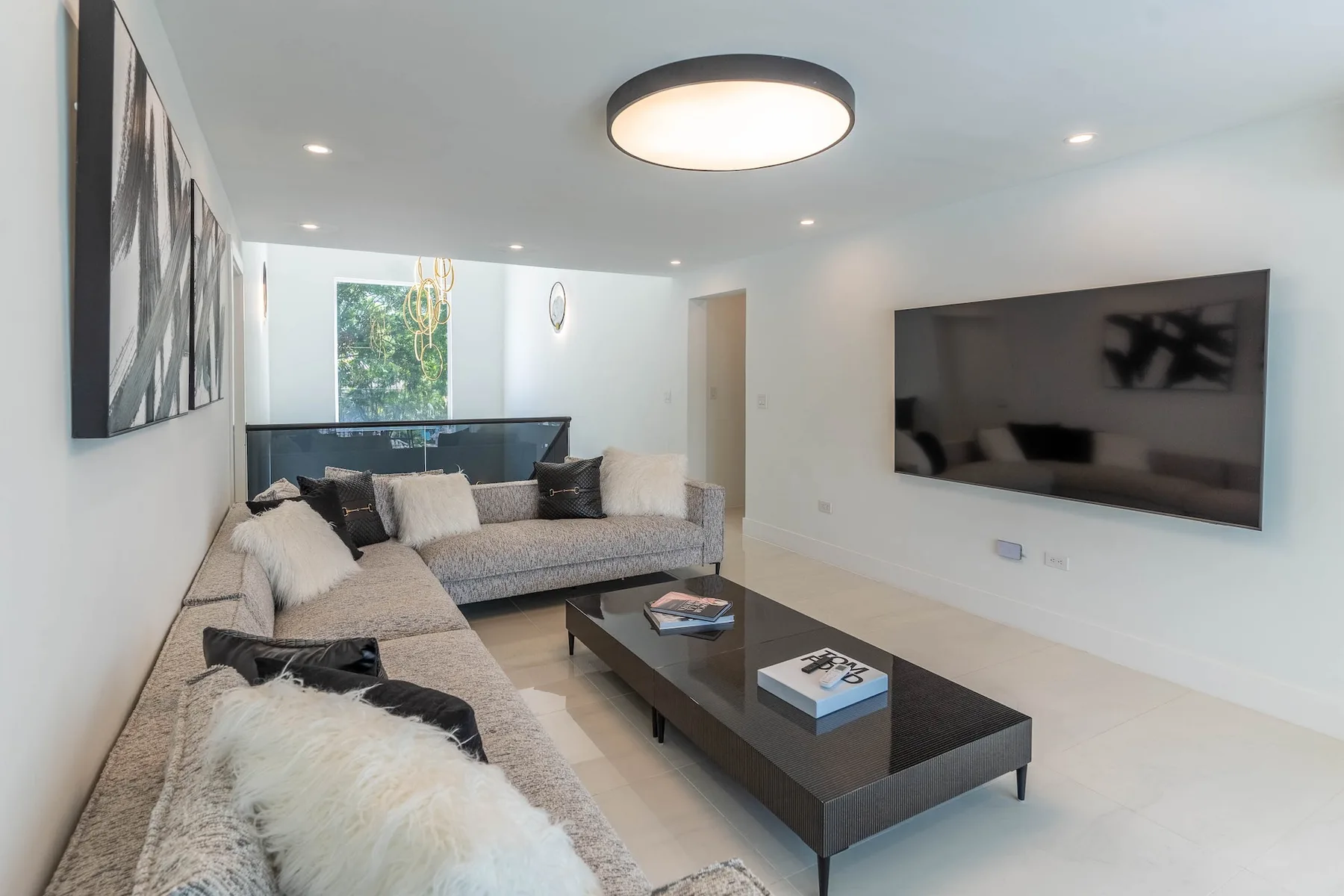 Una sala de estar moderna con asientos en forma de L y un televisor en la pared.