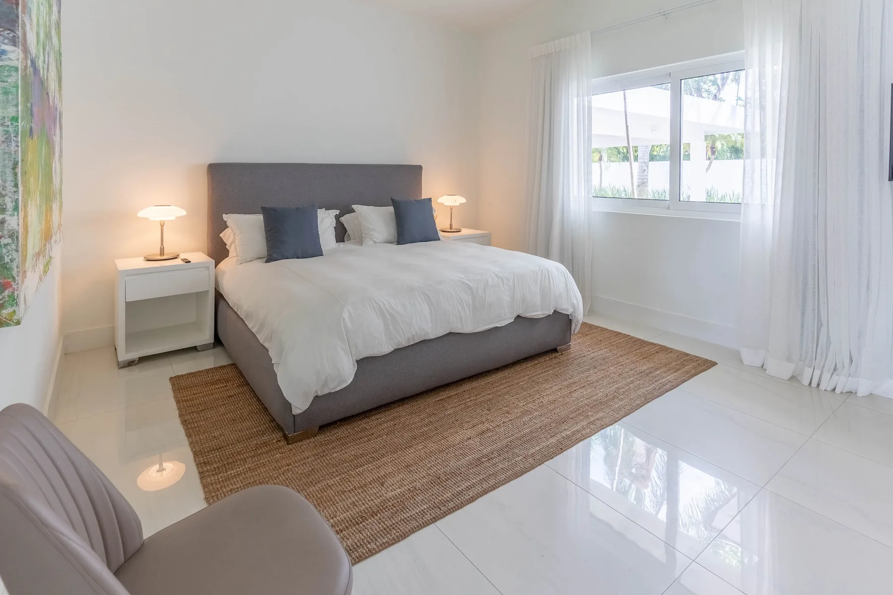 Un dormitorio luminoso con una cama bien tendida junto a una ventana.