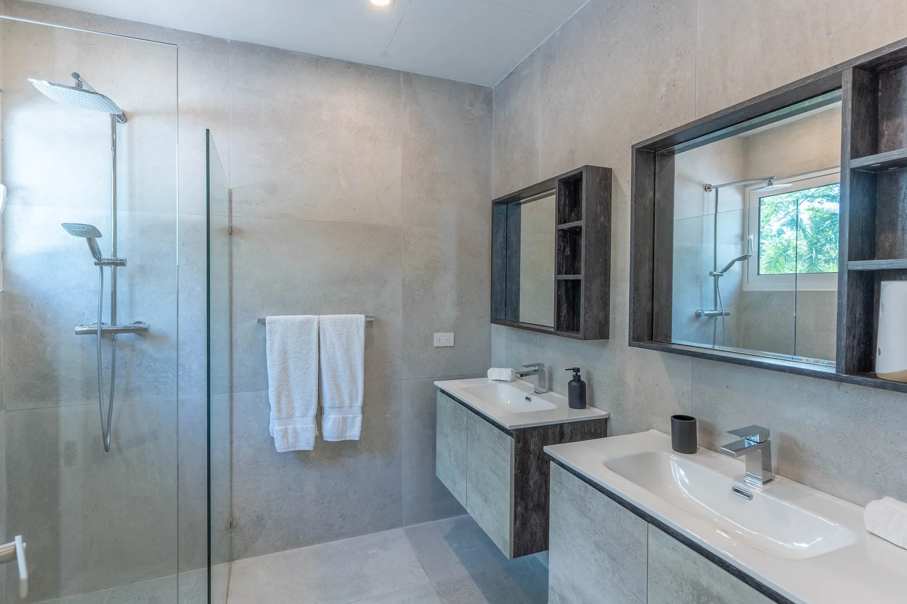 Un baño con una ducha de vidrio y dos zonas de lavabo.