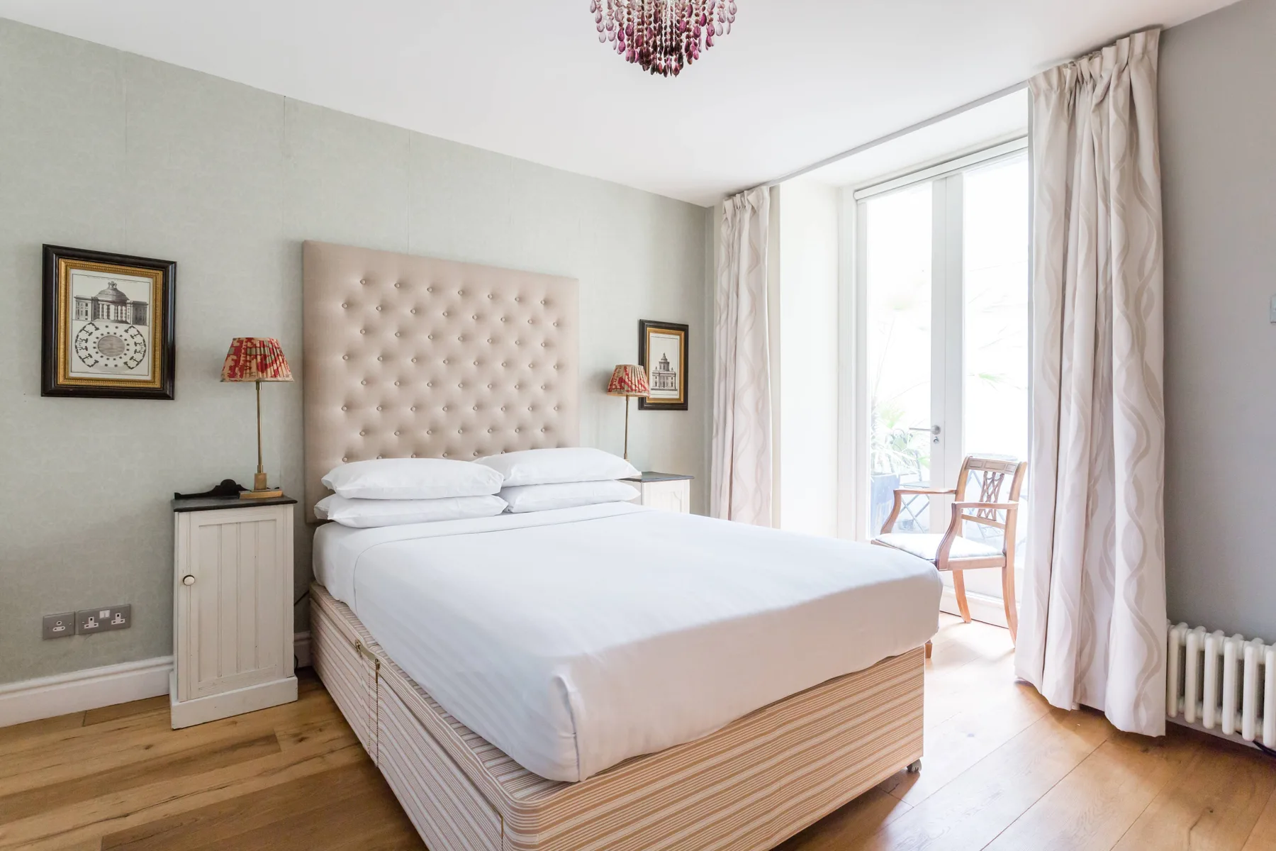 Un dormitorio luminoso con una cama grande y ventanales que dan a un pequeño balcón.