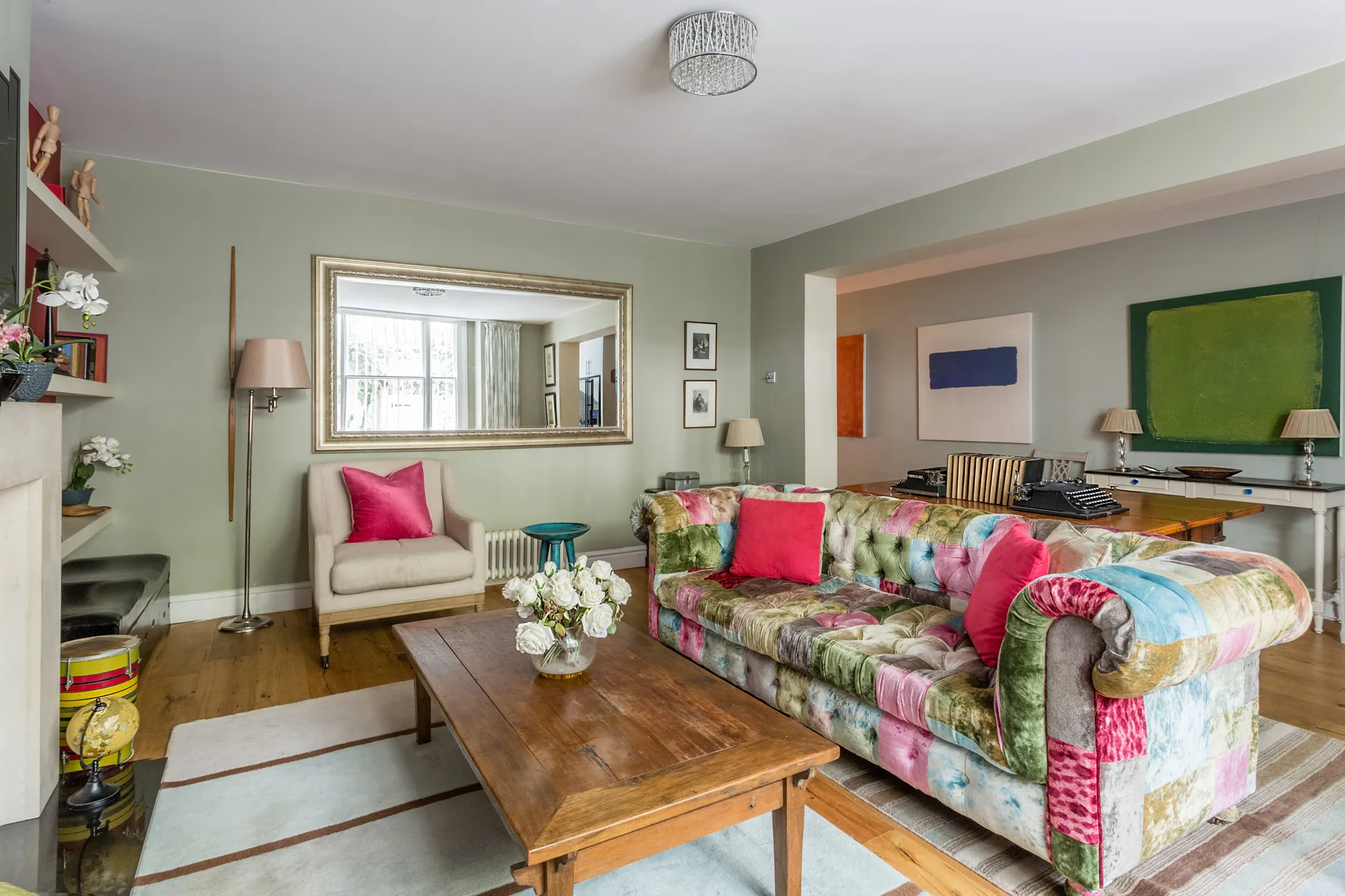 Una sala colorida con un sofá floral, un sillón y una mesa de centro de madera.