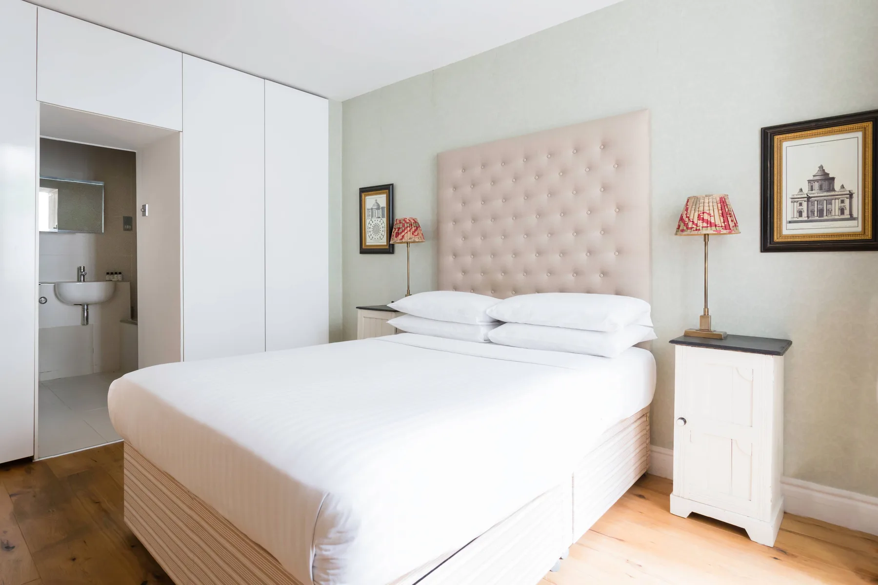 Un dormitorio con una cama bien tendida y un cabecero tapizado claro.