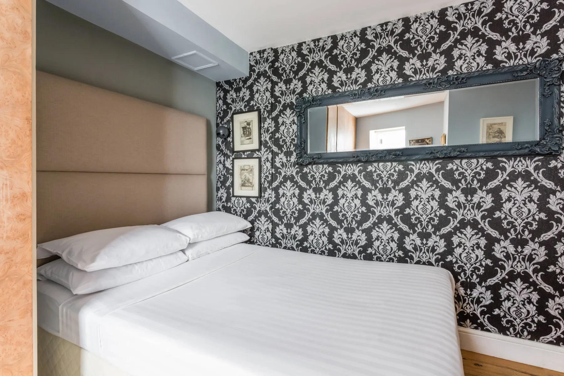 Un dormitorio con ropa de cama blanca y una pared estampada en blanco y negro.
