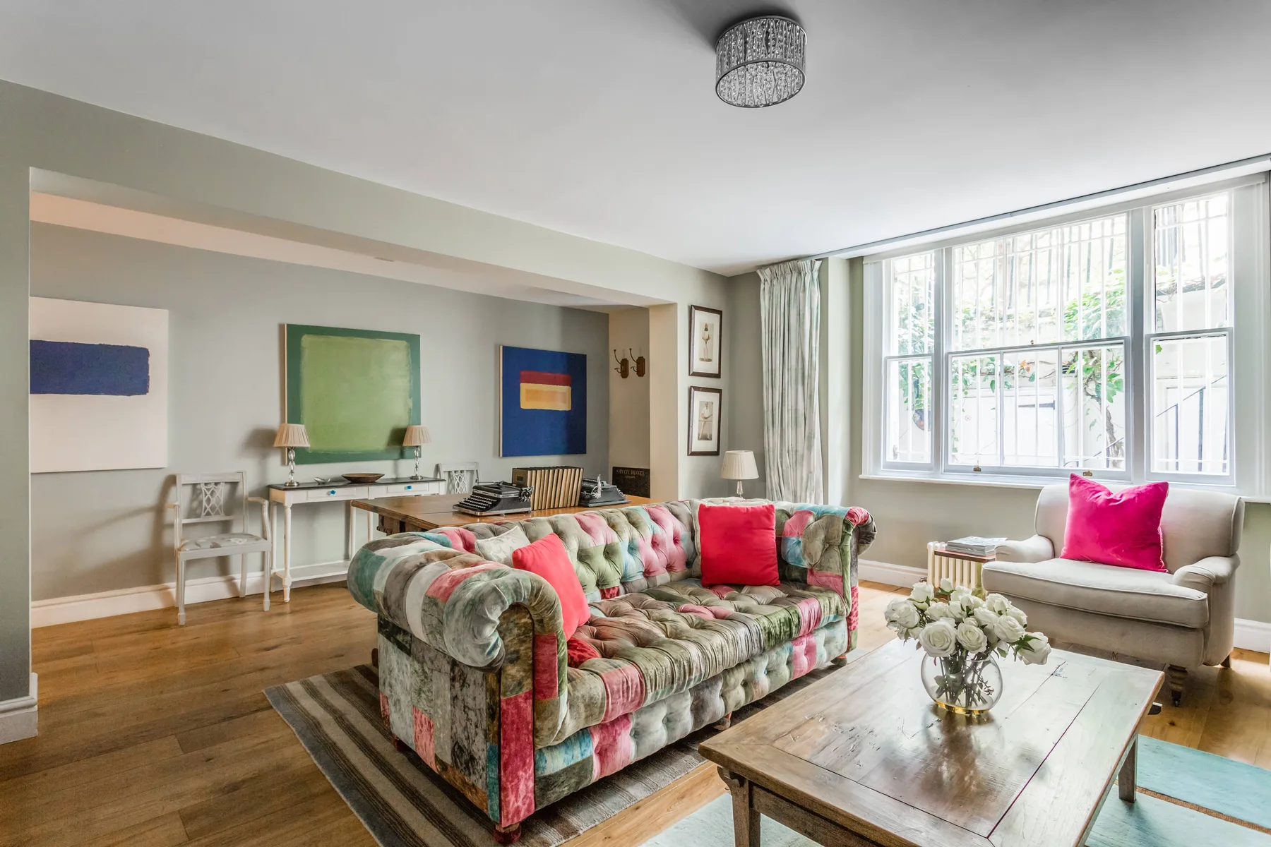 A bright living room with colorful seating beside large windows.