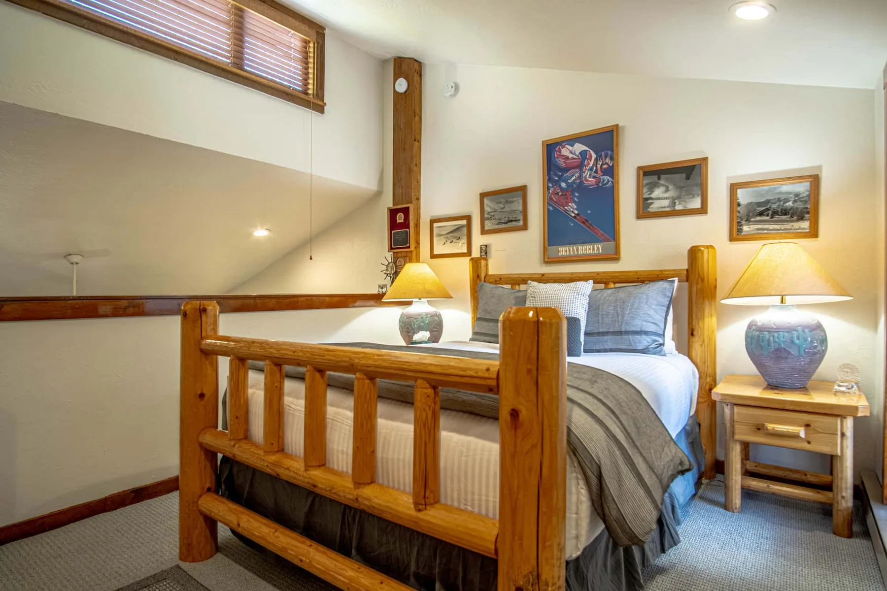 Un dormitorio con una cama de madera, mesitas de noche y cuadros en la pared.
