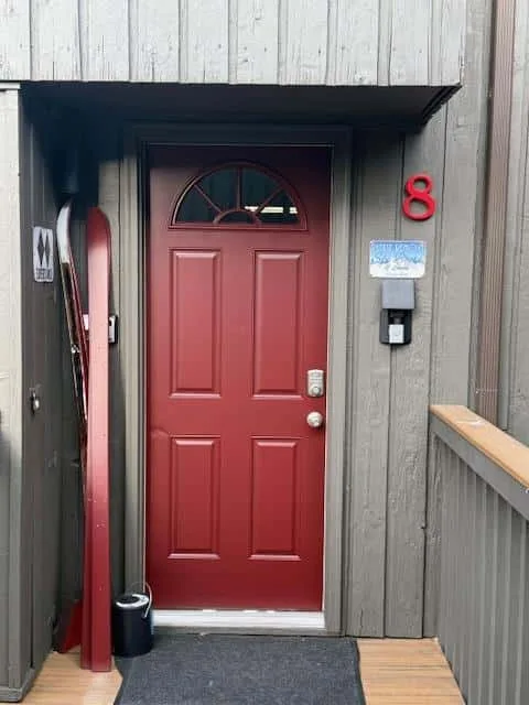 A red entrance door is set into a gray-sided exterior wall.