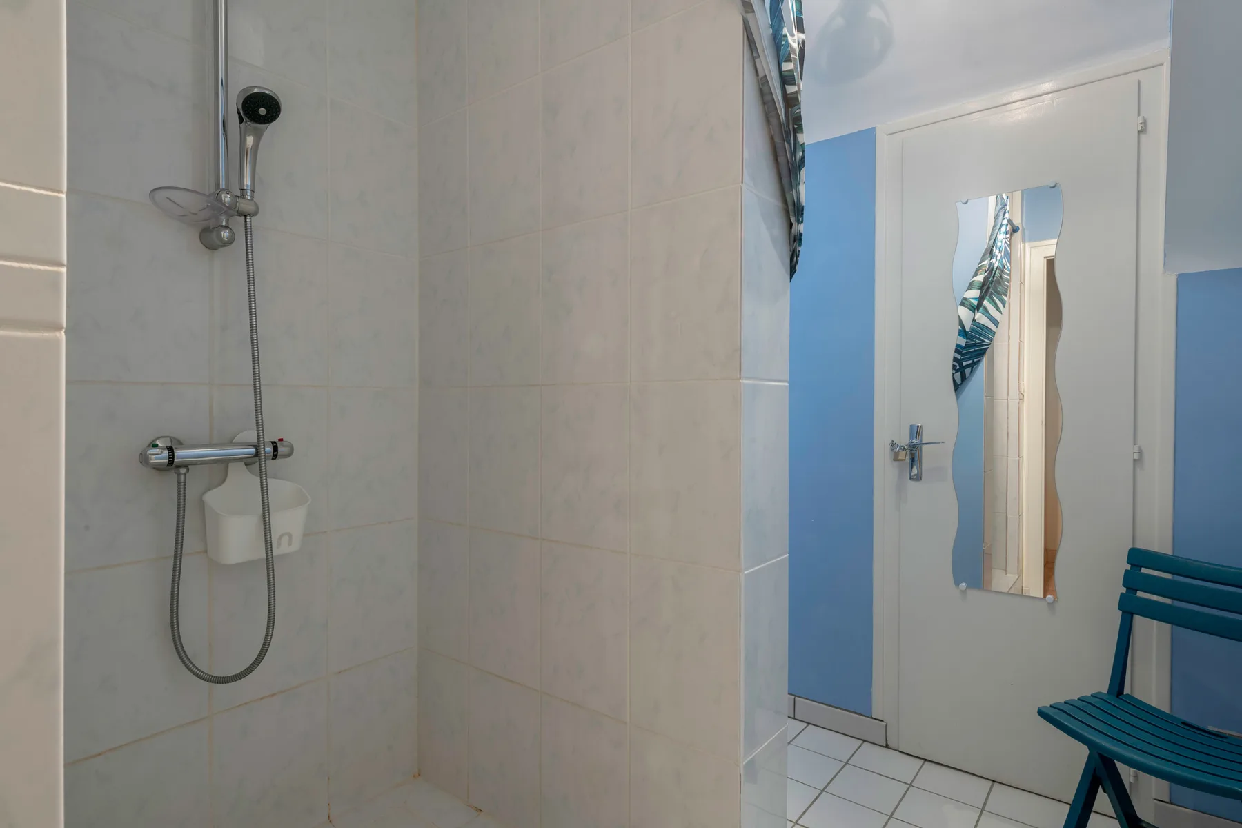A tiled bathroom with a wall-mounted shower beside a door.