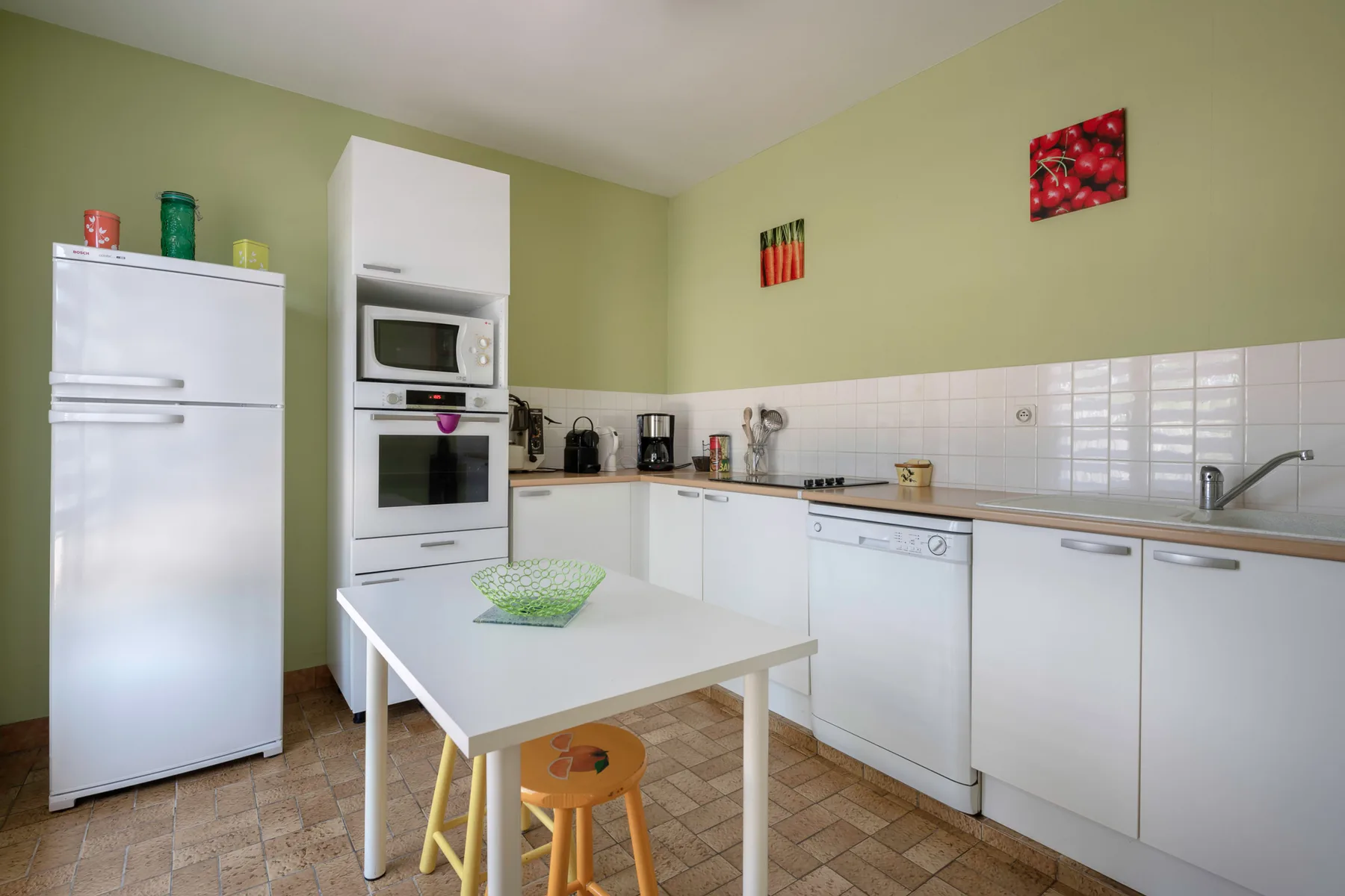 A bright kitchen with white cabinets, appliances, and a small table.