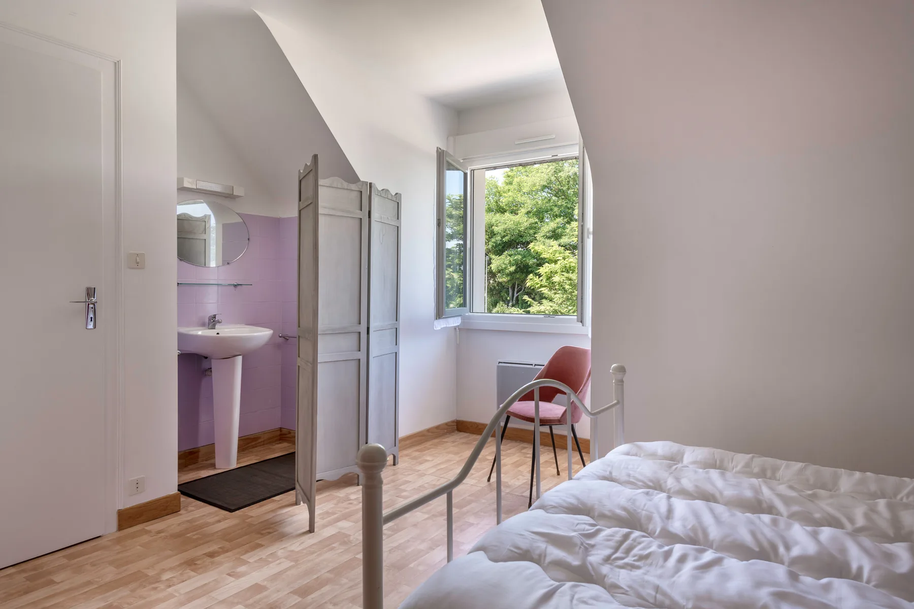 A bedroom with a bed beside an open doorway to a washroom.