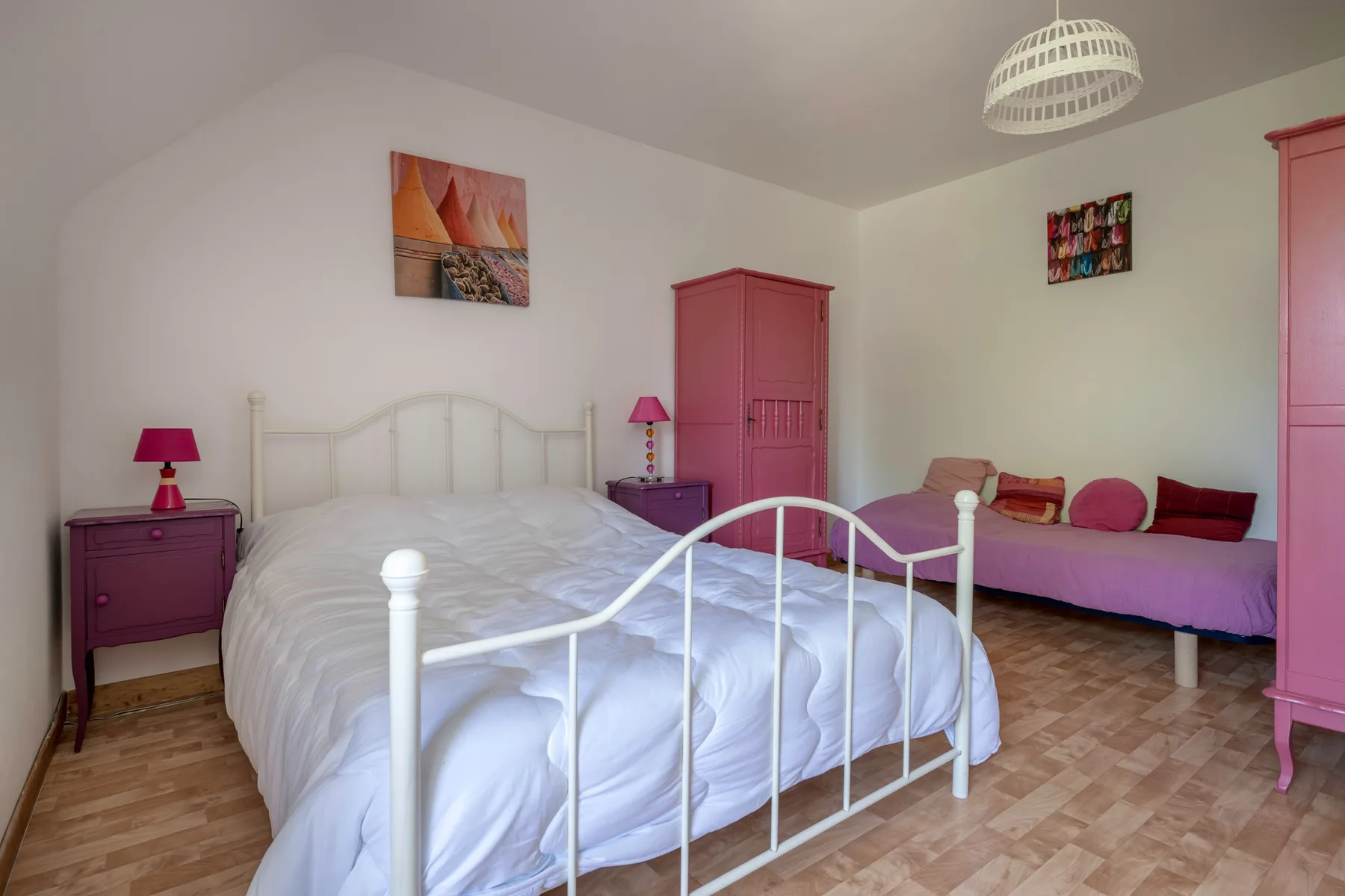 A bedroom with a white bed and a second bed along the wall.