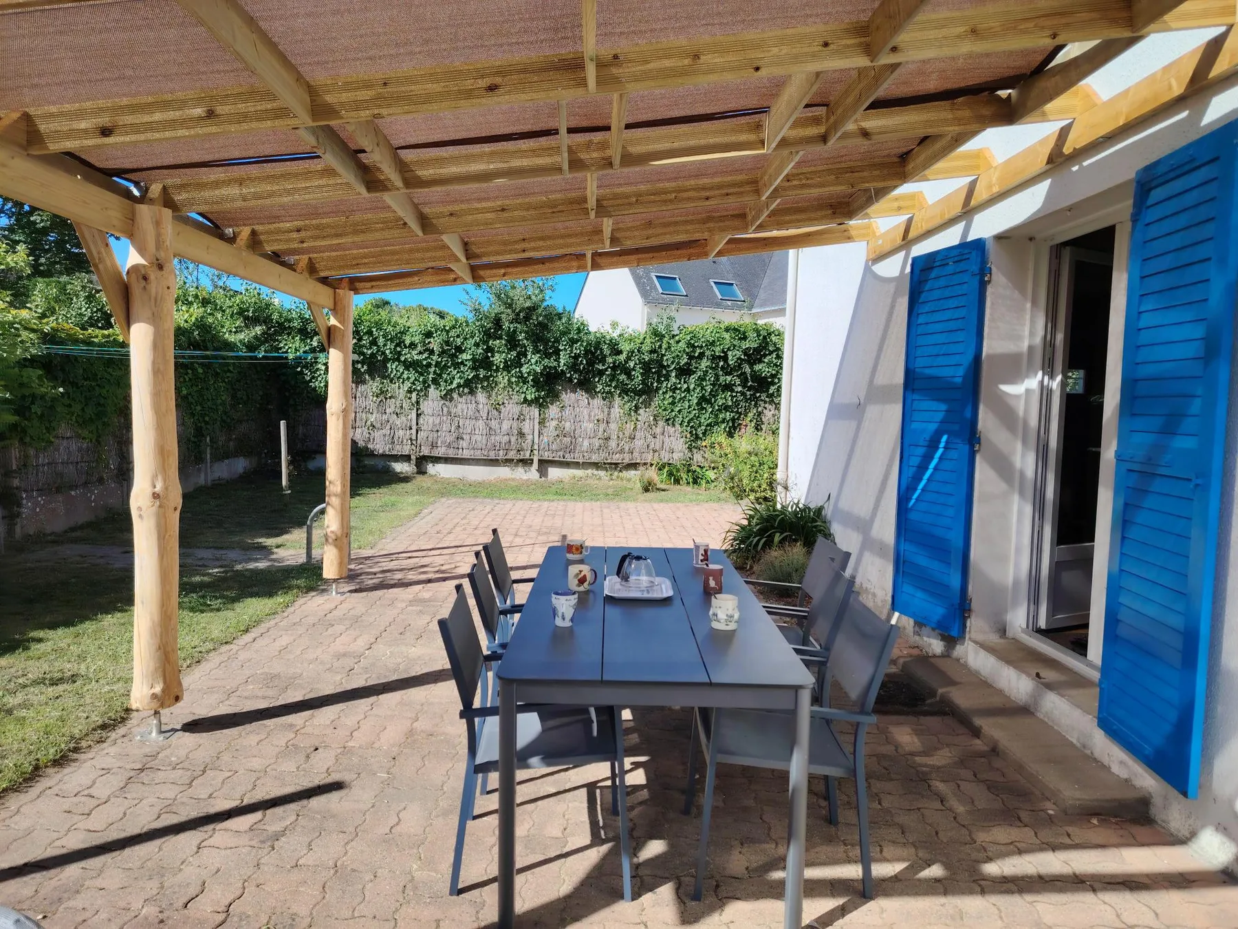 A covered outdoor dining area with a table and seating beside the house.