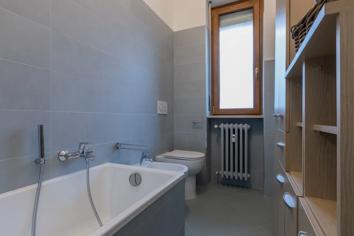 A tiled bathroom with a bathtub, toilet, and window.