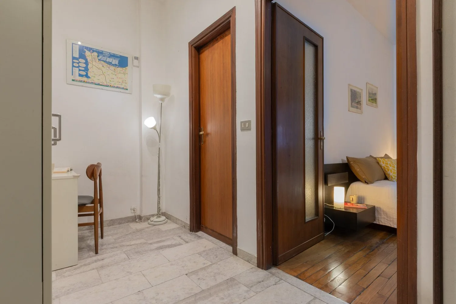 A hallway with a floor lamp and an open doorway into a bedroom.
