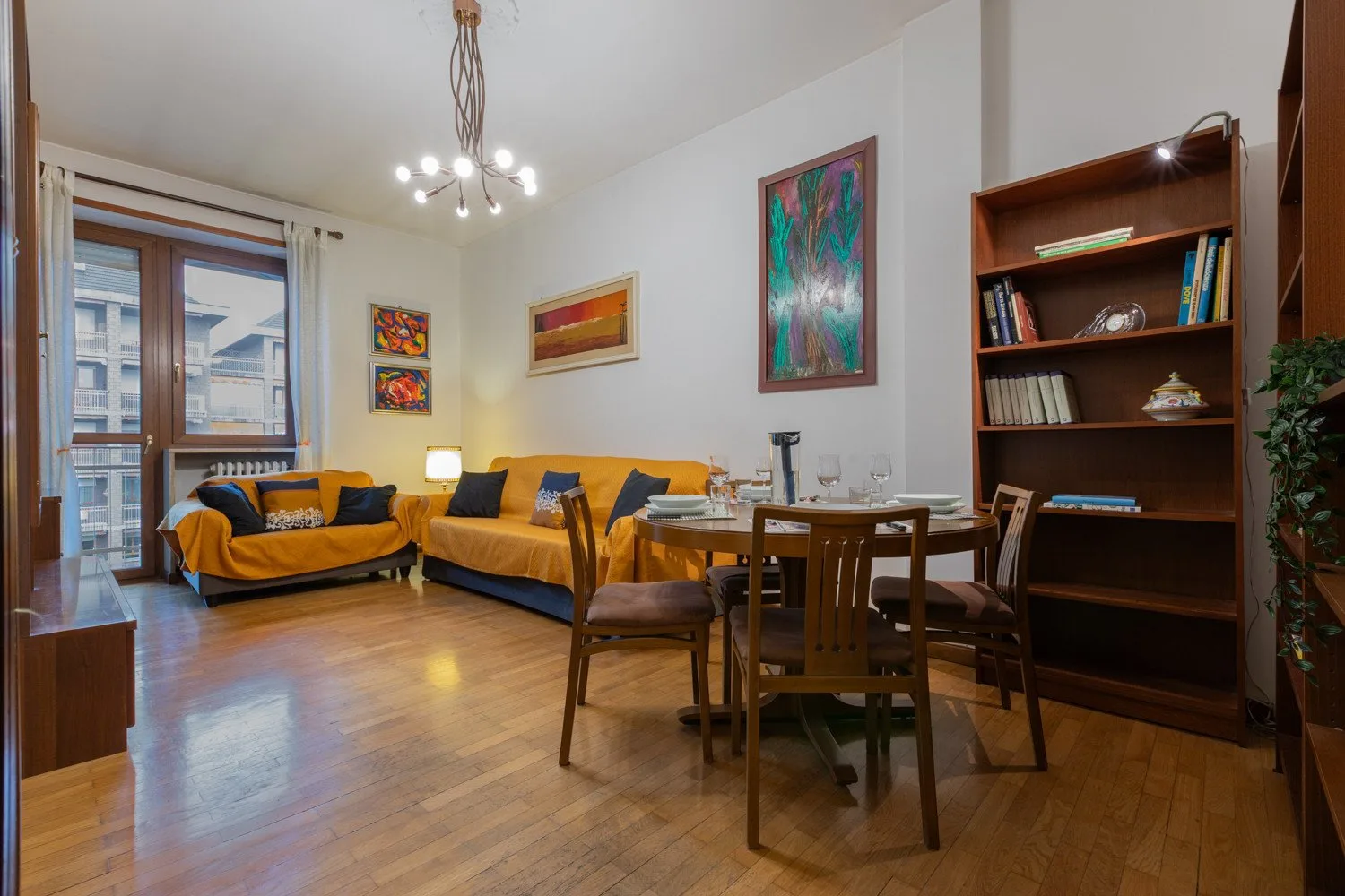 A living and dining room with seating, a dining table, and bookshelves.