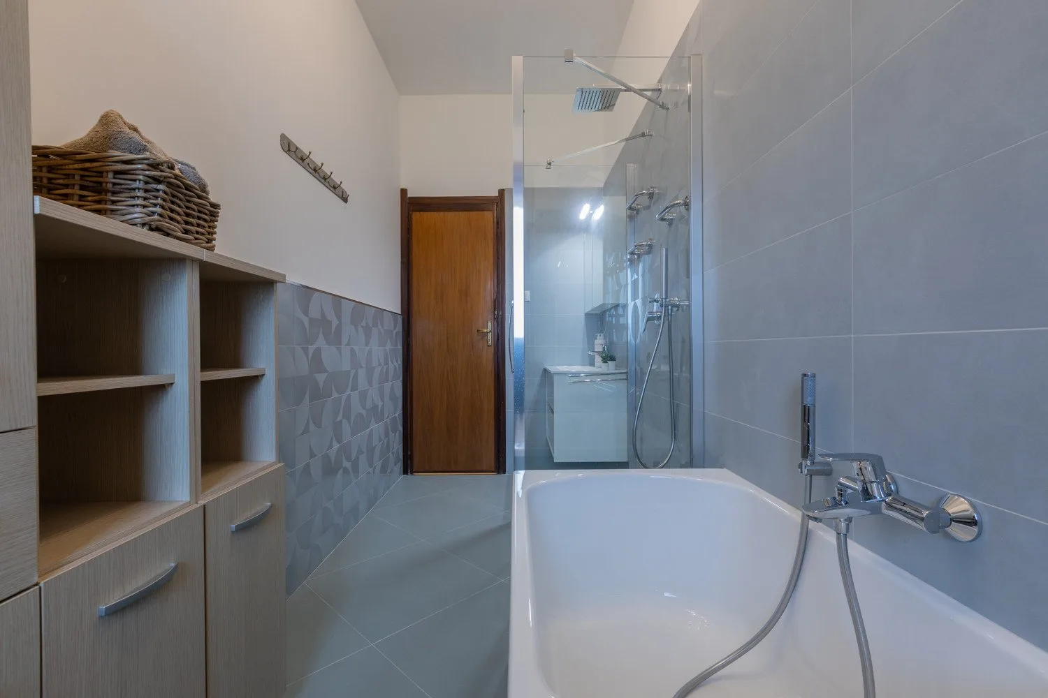 A bathroom with a bathtub, glass shower, and built-in shelving.