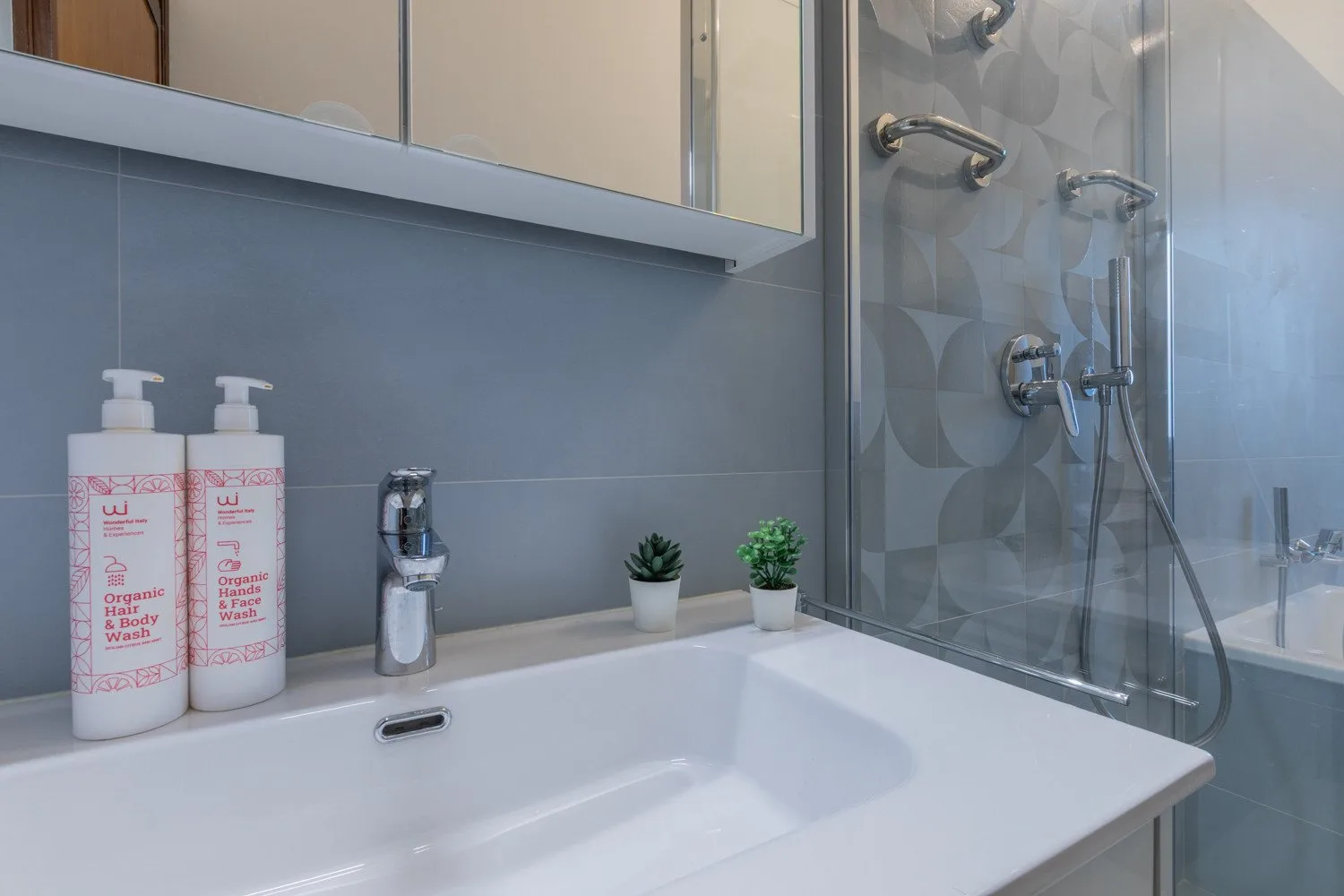 A bathroom vanity with a sink, toiletries, and a glass shower.