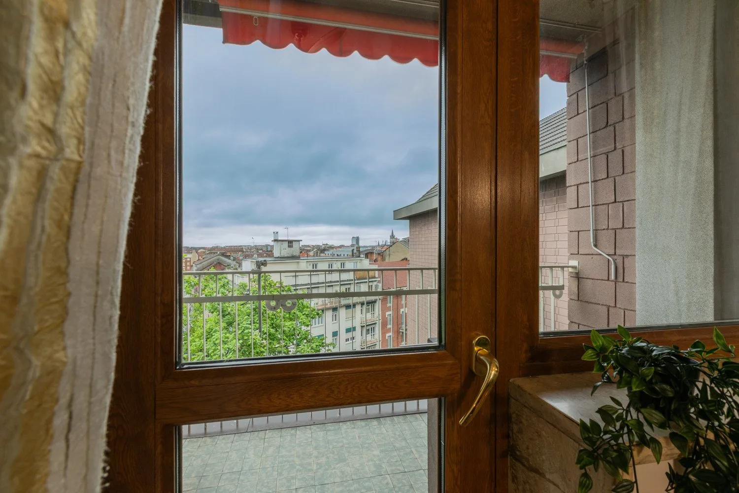A glass balcony door looks out over nearby buildings and greenery.