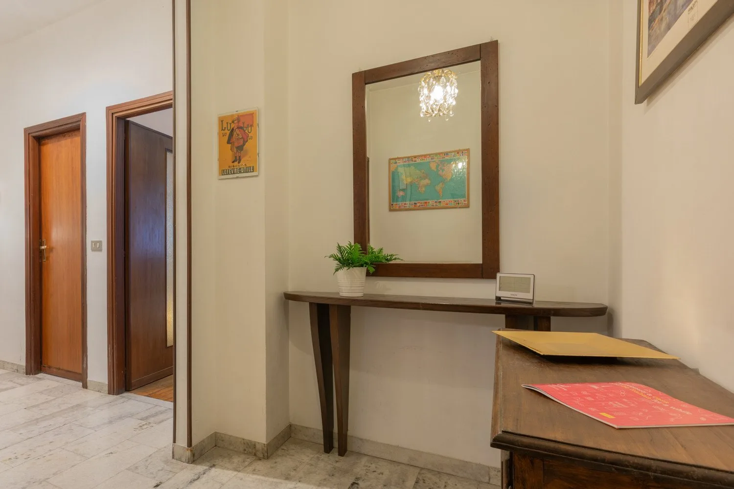 A hallway with a narrow console table, mirror, and framed artwork.