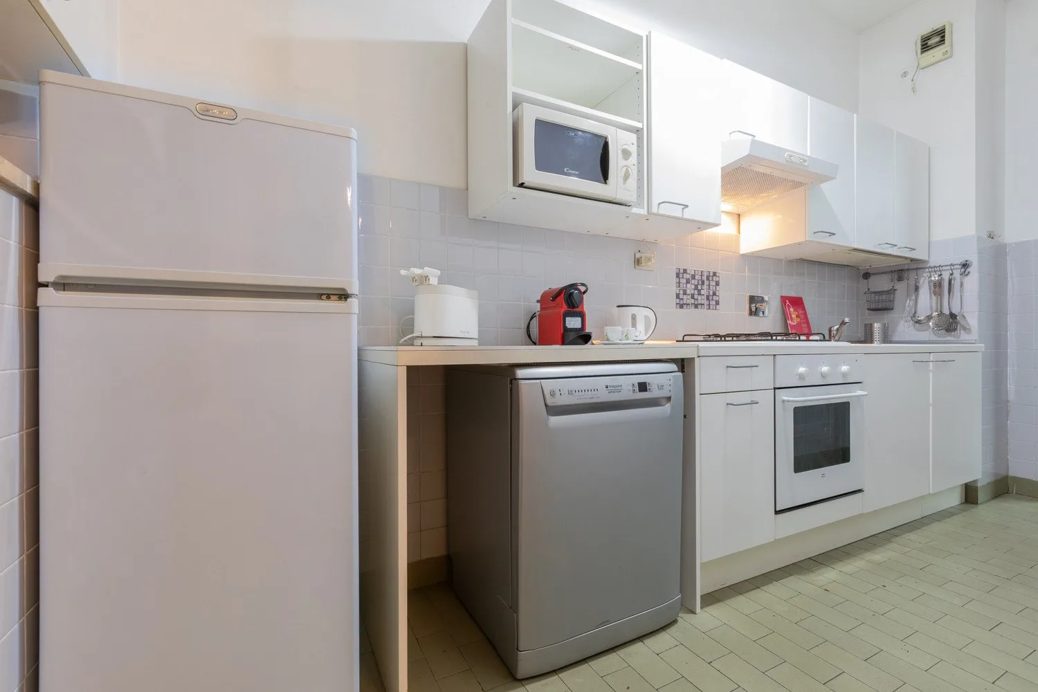 A kitchen with white cabinets, a refrigerator, and appliances along the counter.