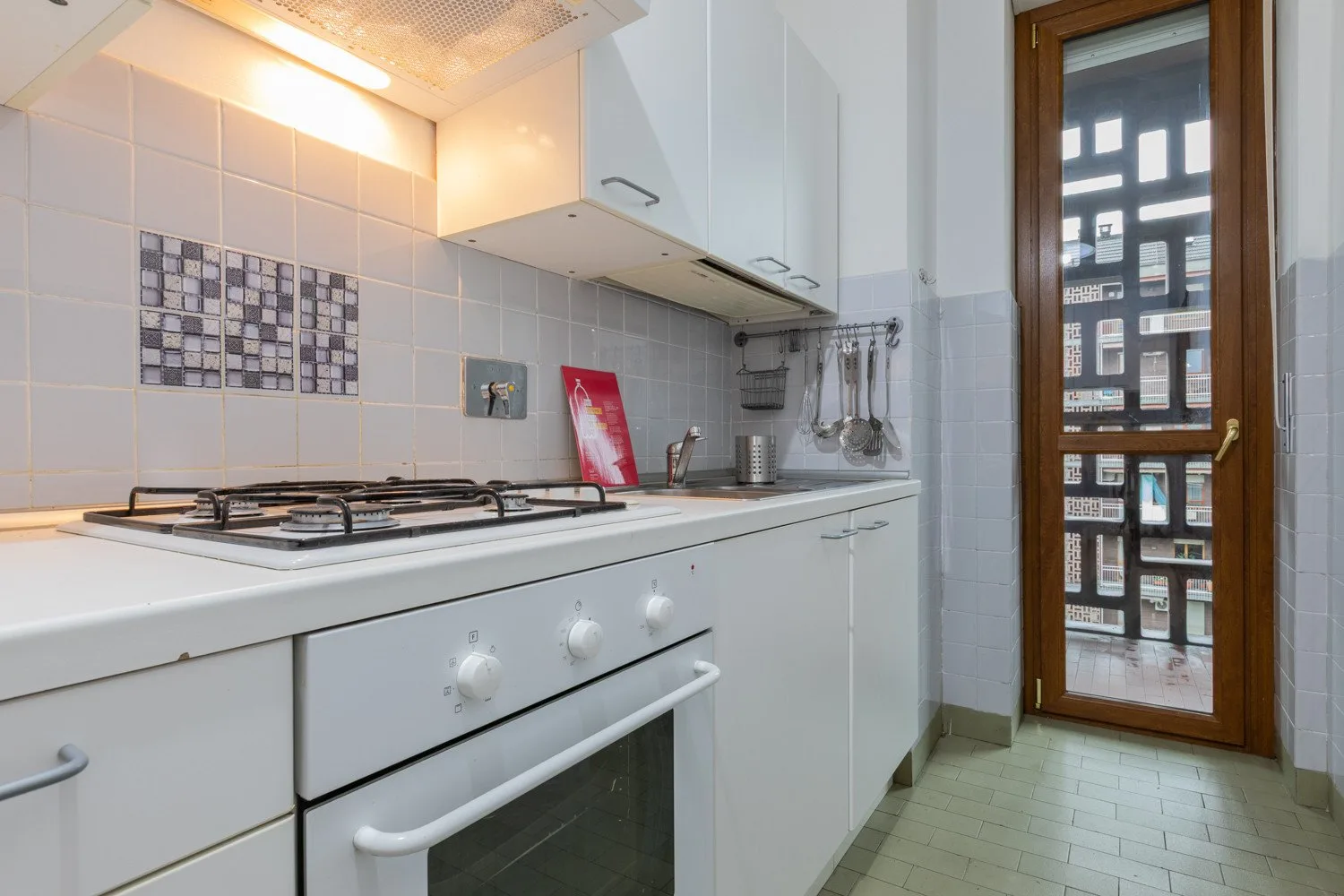 A compact kitchen with a stovetop, oven, and glass-paned door.